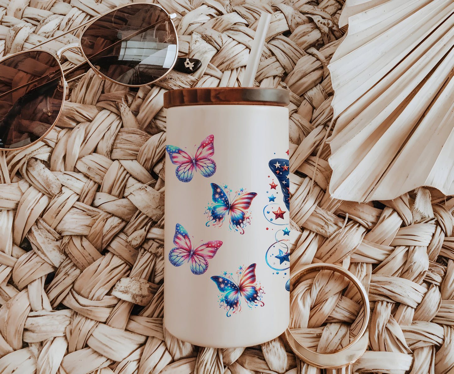a white coffee mug with butterflies on it next to a pair of sunglasses