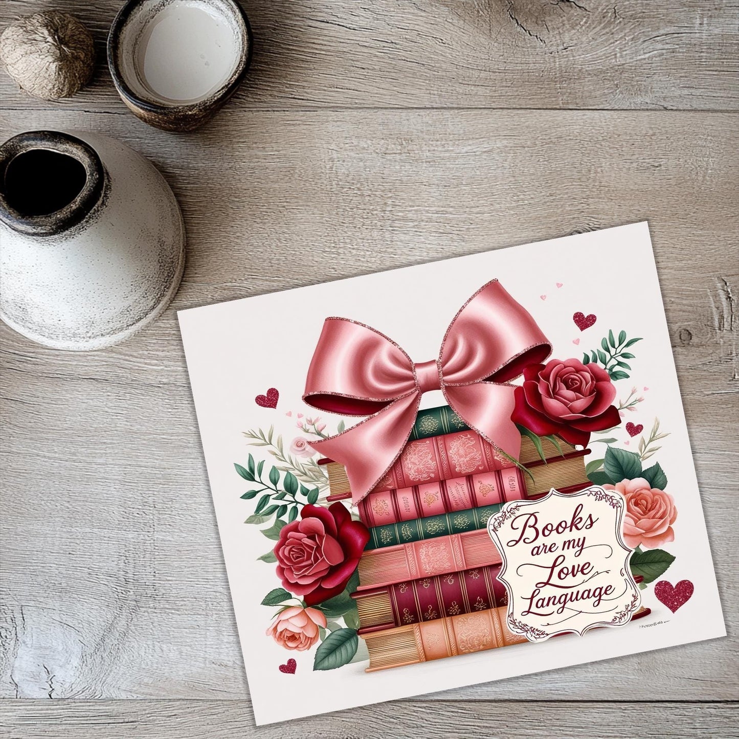a card with a pink bow on top of a stack of books