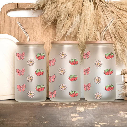 three glass jars with strawberries and bows on them