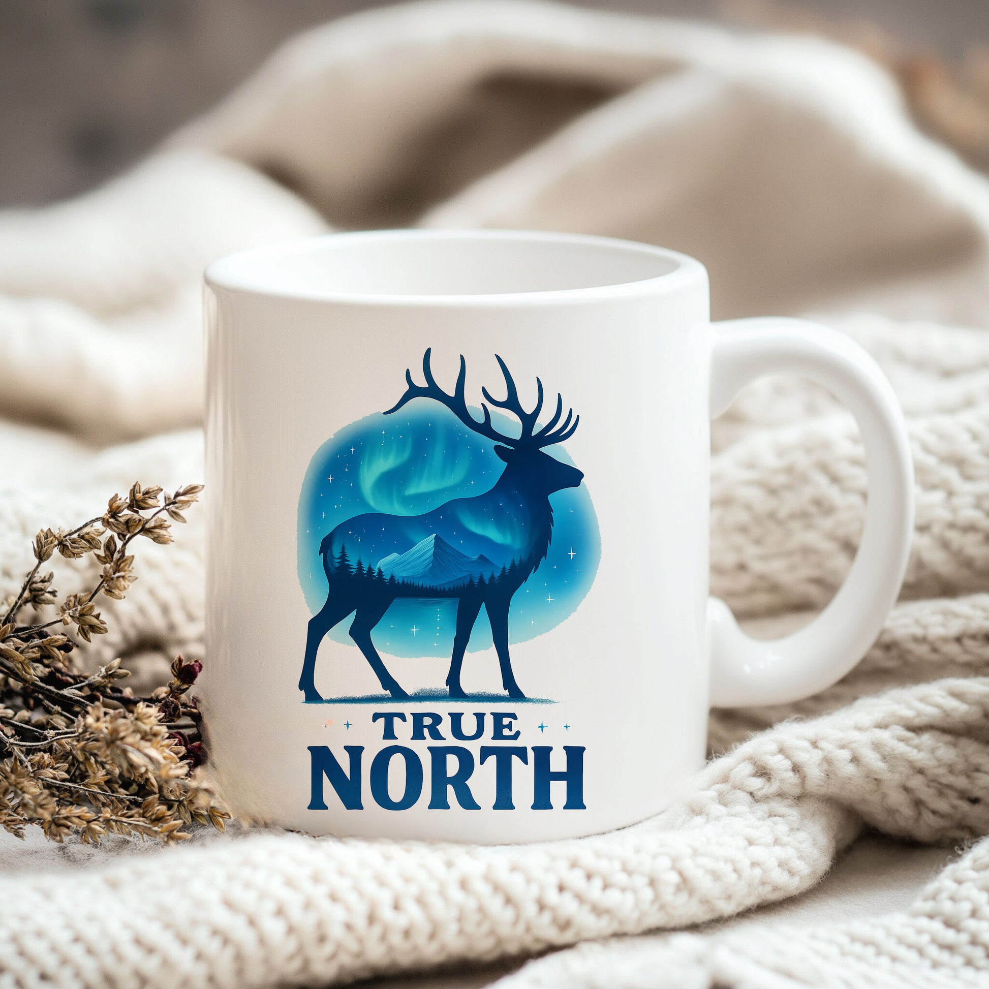 a white coffee mug with a picture of a deer and the words true north on
